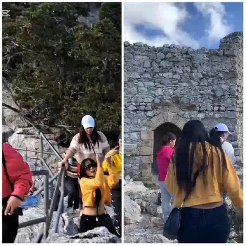 People Climbing Rocky Path and Ruins