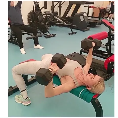 Woman Bench Pressing Weights at Gym