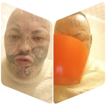 Person with Facial Tattoos Holding Orange