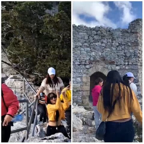 People Climbing Rocky Path and Ruins