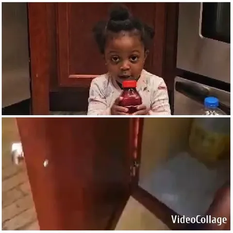 Child Holding Red Bottle in Kitchen